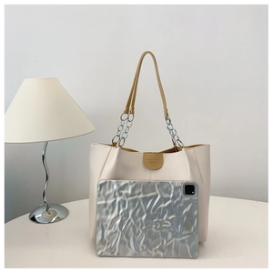 Large cream tote bag with brown straps and chain detail next to a tablet for size reference