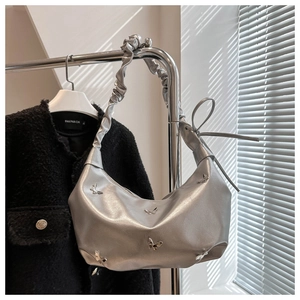 Détail du sac cabas argenté avec papillon en métal 3D et bandoulière plissée élégante