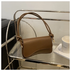 Detail of a brown leather shoulder bag with asymmetrical base and elegant knotted straps
