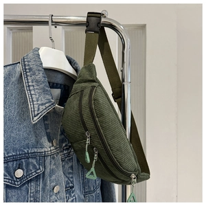 Close-up of a green corduroy crossbody waist bag with textured fabric and zipper details