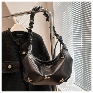 Détail du sac croissant en cuir noir avec papillons argentés et bandoulière froncée