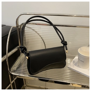 Close-up of black matte leather bag featuring a chunky rope knot strap and gold metal hardware