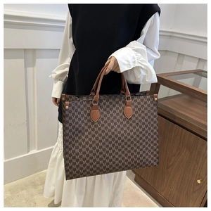 Sac cabas tendance avec imprimé monogramme M et anses en cuir marron porté par mannequin