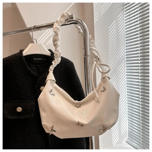 Détail du sac hobo blanc avec ornements papillon en métal et bandoulière à volants