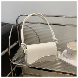 Detailed close-up of white faux leather shoulder bag with knotted strap and metal hardware