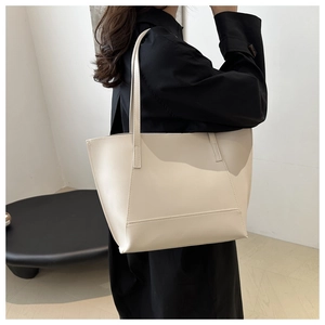 Chic cream white leather tote bag shown on a model with a minimalist black dress
