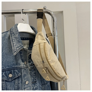 Detail of beige corduroy waist bag with dual zippers and adjustable woven strap
