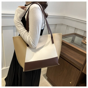 Detail of large patchwork leather tote bag with beige and brown blocks on model