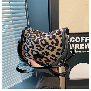 Detail of leopard print fabric bag featuring black zipper and FASHION label