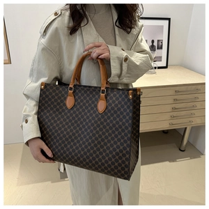 Détail du sac cabas vintage avec motif classique, anses en cuir brun et finitions dorées