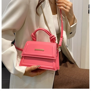 Detail view of pink square bag with knotted handle and golden decorative metal bar