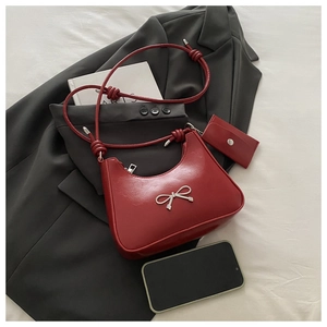 Detail of red crescent underarm bag with silver metallic bow and matching mini pouch