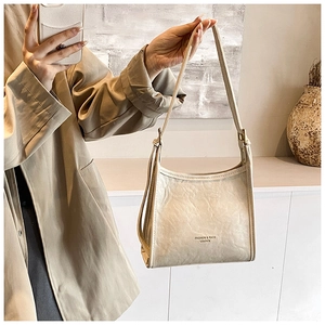 Detailed texture of beige pleated leather tote bag with elegant typography and long shoulder strap