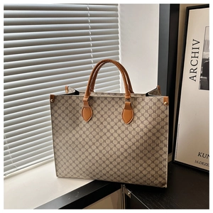 Détail des poignées en cuir marron avec rivets dorés sur un grand sac cabas vintage