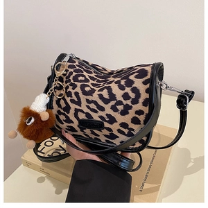 Detail of leopard print crossbody bag with fashion label and plush doll pendant accessory