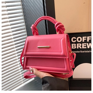 Detail of a chic magenta mini handbag with gold metal clasp and knotted top handle design
