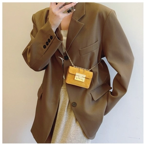 Micro mini crossbody bag in yellow suede with gold chain strap on a brown oversized blazer