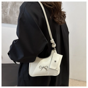 Detailed view of white shoulder bag with silver bow accent and mini side coin purse