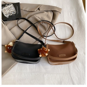 Detail of matte faux leather round crossbody bags in black and brown with plush charms