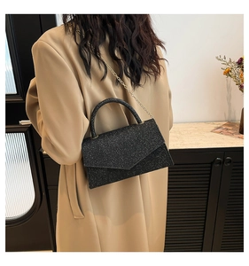 Detail of the black glitter shoulder bag with a gold chain strap and a top handle