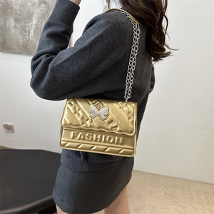 Golden quilted crossbody bag with silver butterfly and metal chain strap for women