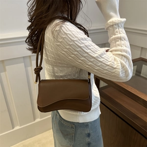 Minimalist dark brown leather shoulder bag for women with unique curved flap and gold metal trim