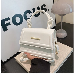Detail of cream white handbag with unique knotted handle and gold metal fastener