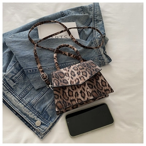 Leopard print mini crossbody bag with silver buckle detail placed on denim jacket