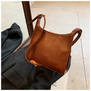 Detail of vintage brown leather tote bag showing textured surface and shoulder strap