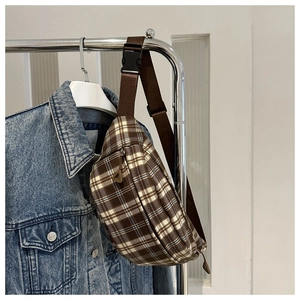 Détail d'un sac bandoulière à carreaux marron avec sangle réglable et boucle en plastique
