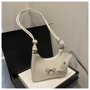 Detail of cream white underarm bag with silver bow ornament and small side pouch