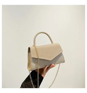 Detail of gold glitter party handbag with metal chain strap and top handle held by hand