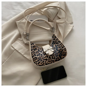 Detail showing leopard print crescent bag with silver bow hardware on a beige blazer