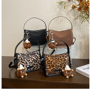 Retro shoulder bags in solid and leopard prints with plush monster charms on display