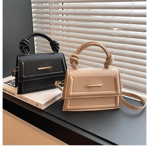 Detail of minimalist leather crossbody bags with woven handles in black and beige colors