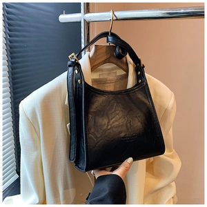 Detail of vintage black tote bag with wrinkled PU leather texture and gold hardware
