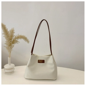 Macro shot of white waffle textured tote bag with dark brown leather logo tag