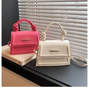 Detail of fuchsia and cream mini trapezoid bags with knotted handles and gold hardware