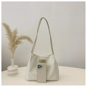 Detail of white waffle texture tote bag with leather logo tag and slim shoulder straps