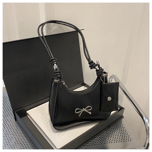 Black patent leather underarm bag featuring a silver bow detail and matching coin purse