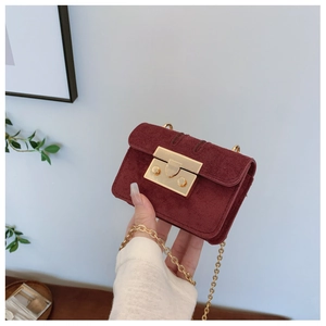 Close-up of wine red suede mini bag featuring a polished gold rectangular metal buckle