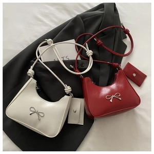 Detail of hobo bags with metallic bow buckle and knotted strap on grey blazer