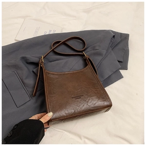 Detail of vintage brown PU leather tote bag with embossed text and bronze hardware