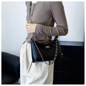 Detail of classic black quilted shoulder bag with gold chain strap and twist lock detail