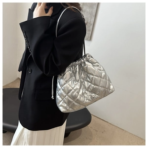Macro detail of silver quilted tote bag featuring a metallic finish and bow accent