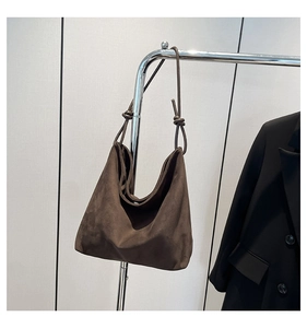 Detail of dark brown suede hobo bag featuring decorative shoulder strap knots