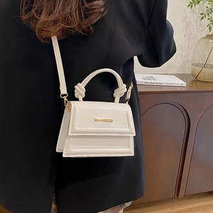 Minimalist white leather crossbody bag with gold metal trim and knotted handle detail