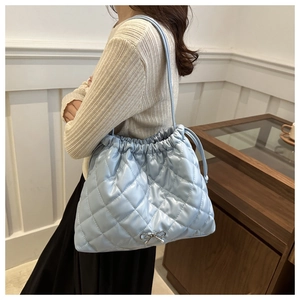 Detail of light blue quilted tote bag with silver bow accent and fine leather straps