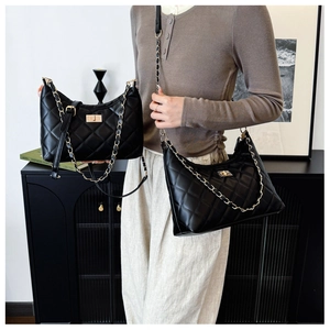 Close-up of black quilted shoulder bag with gold chain strap and metal lock detail