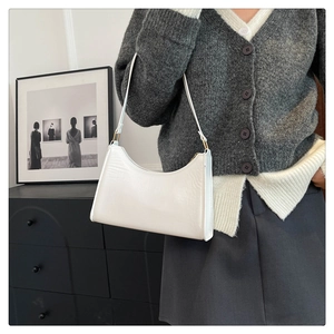 Detail of white minimalist underarm shoulder bag with sleek curved silhouette and metal link